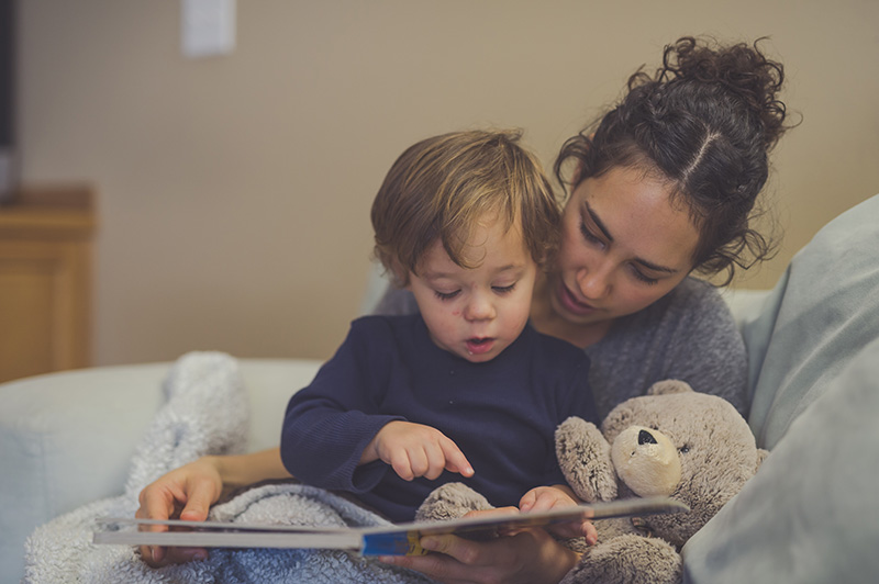 Mom and Son Reading Book Together in Living Room