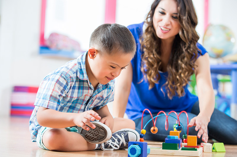 A childcare teacher and one of their students playing.