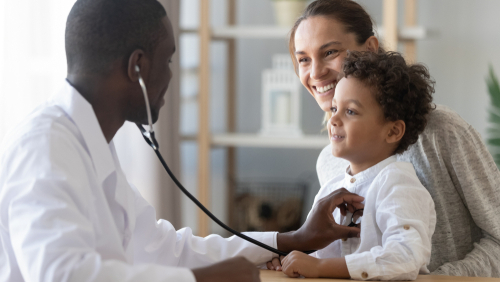 Photo of medical doctor holding a stethescope examing a child with their mother