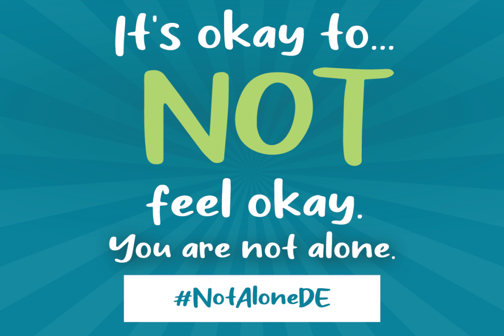 Graphic with a blue starburst in the background of text that reads: It's okay to..not feel okay. You are not alone. #NotAloneDE 