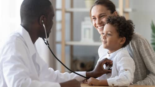 A medical doctor holding a stethescope examing a child with their mother