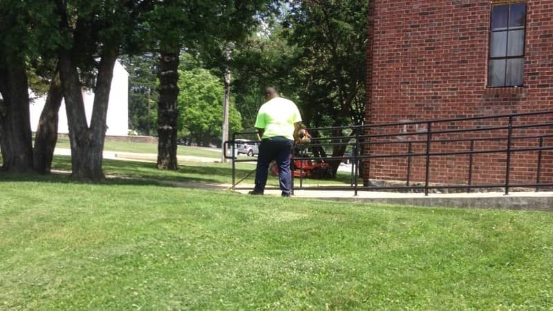 A maintenance worker trimming grass